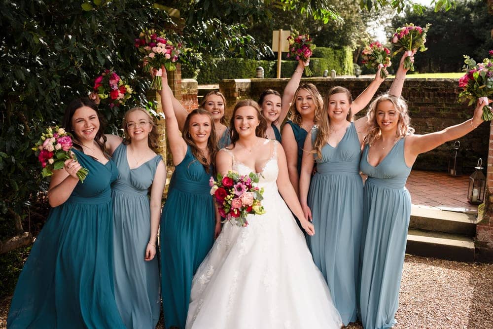 Wedding photograph by Sky Photography — a bride and her bridesmaids laugh together, raising their bouquets